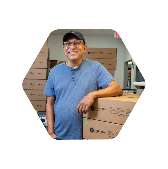Smiling man in a ball cap with arm resting on stack of boxes with Fortess logos